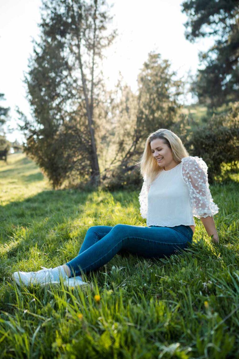 junge Frau sitzt im Gras in der Abendsonne