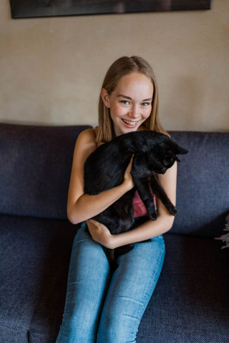 Mädchen spielt auf Sofa mit Katze