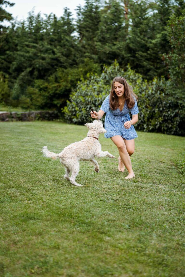 junge Frau spielt im Garten mit ihrem Hund