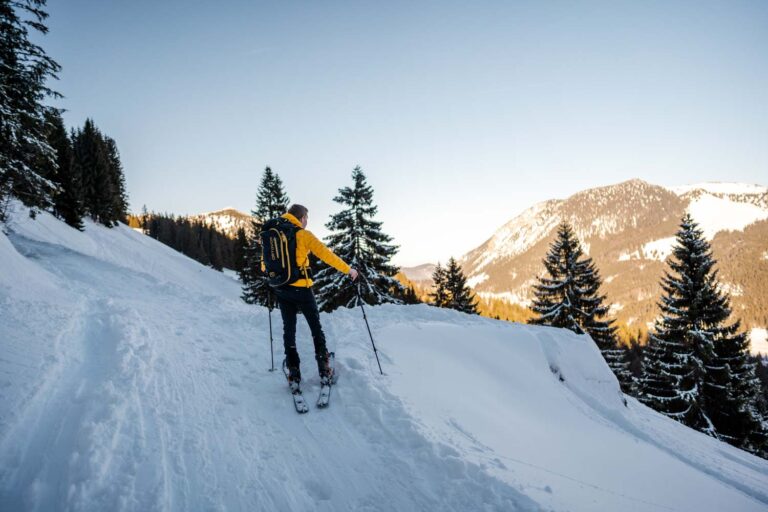 junger Mann blickt in die Ferne beim Skitour laufen